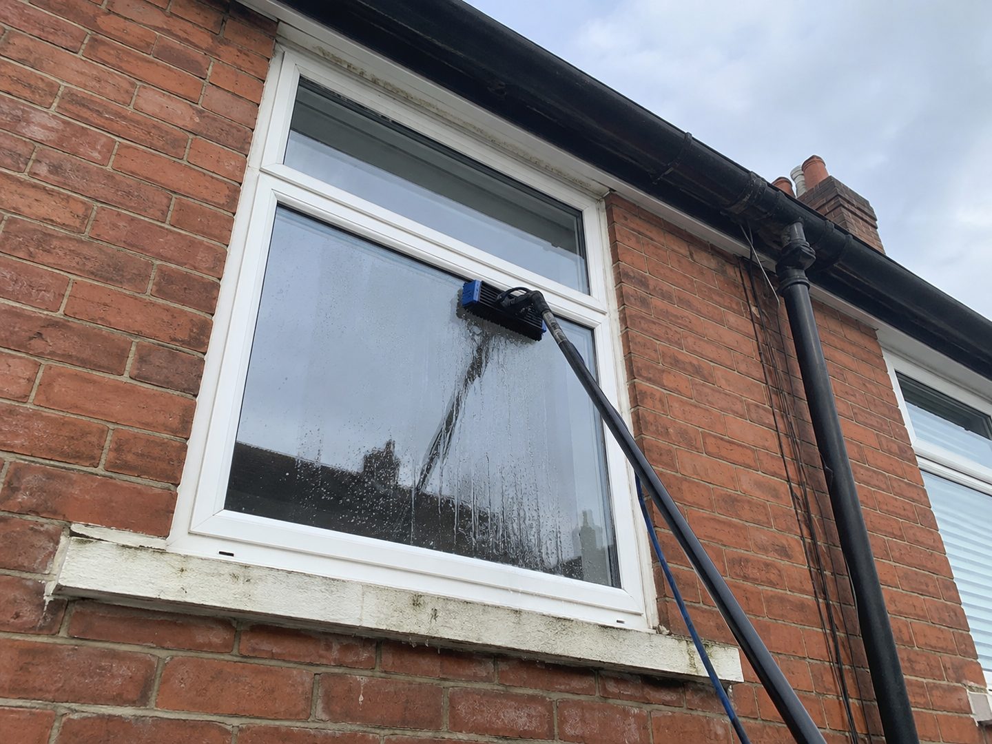 Cleaning an upstairs window from the ground with a water-fed pole